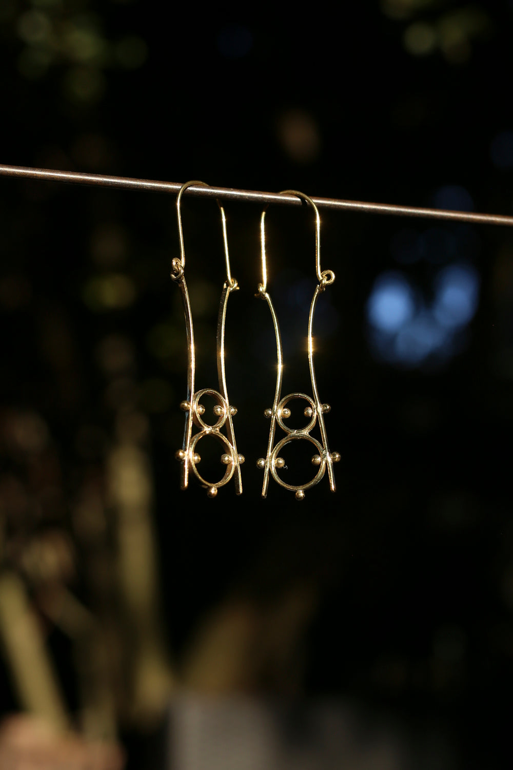 brassearrings hanging on a rod with a dark background