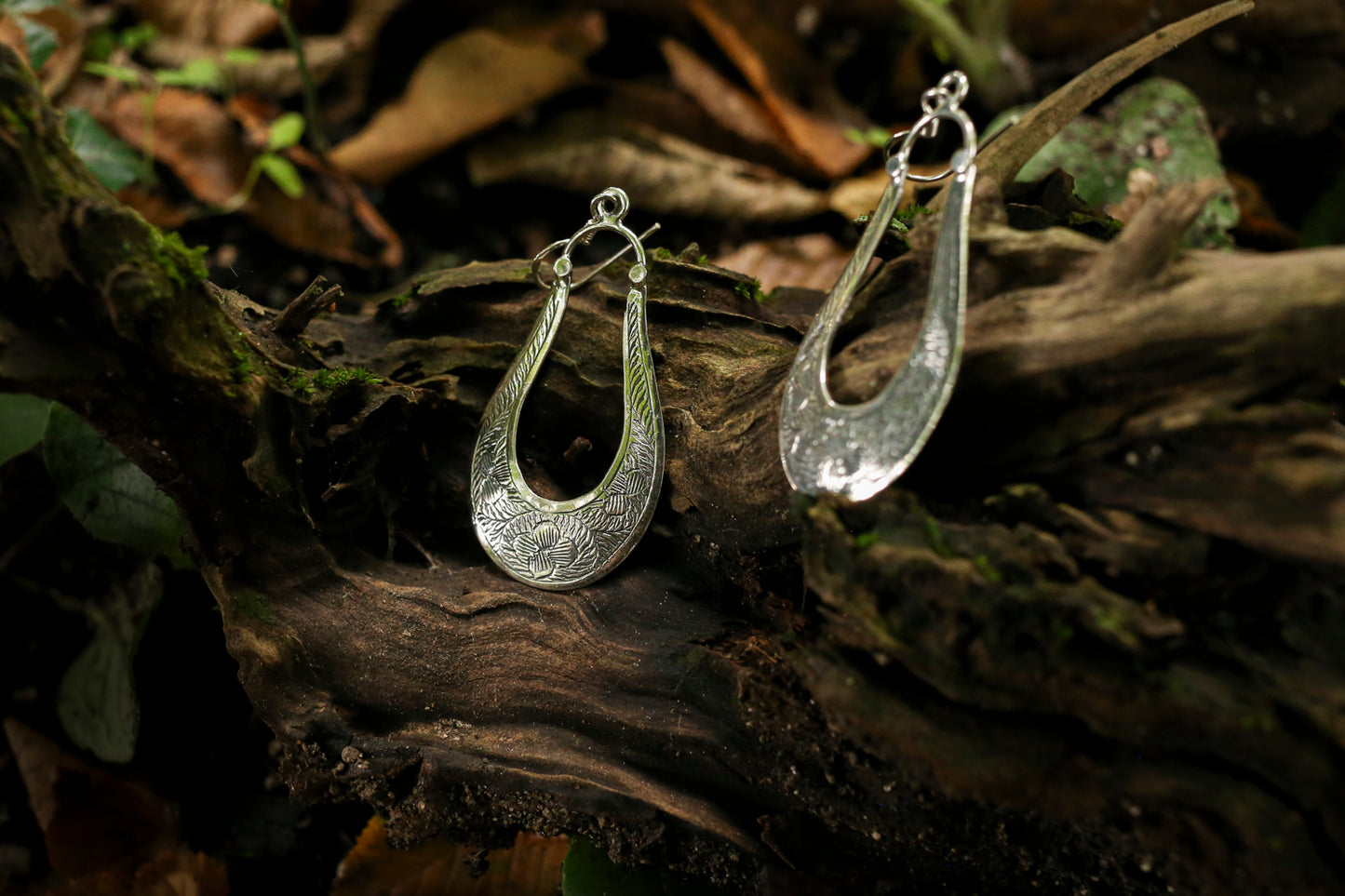 Silver hoop earrings on a wooden surface with a natural background