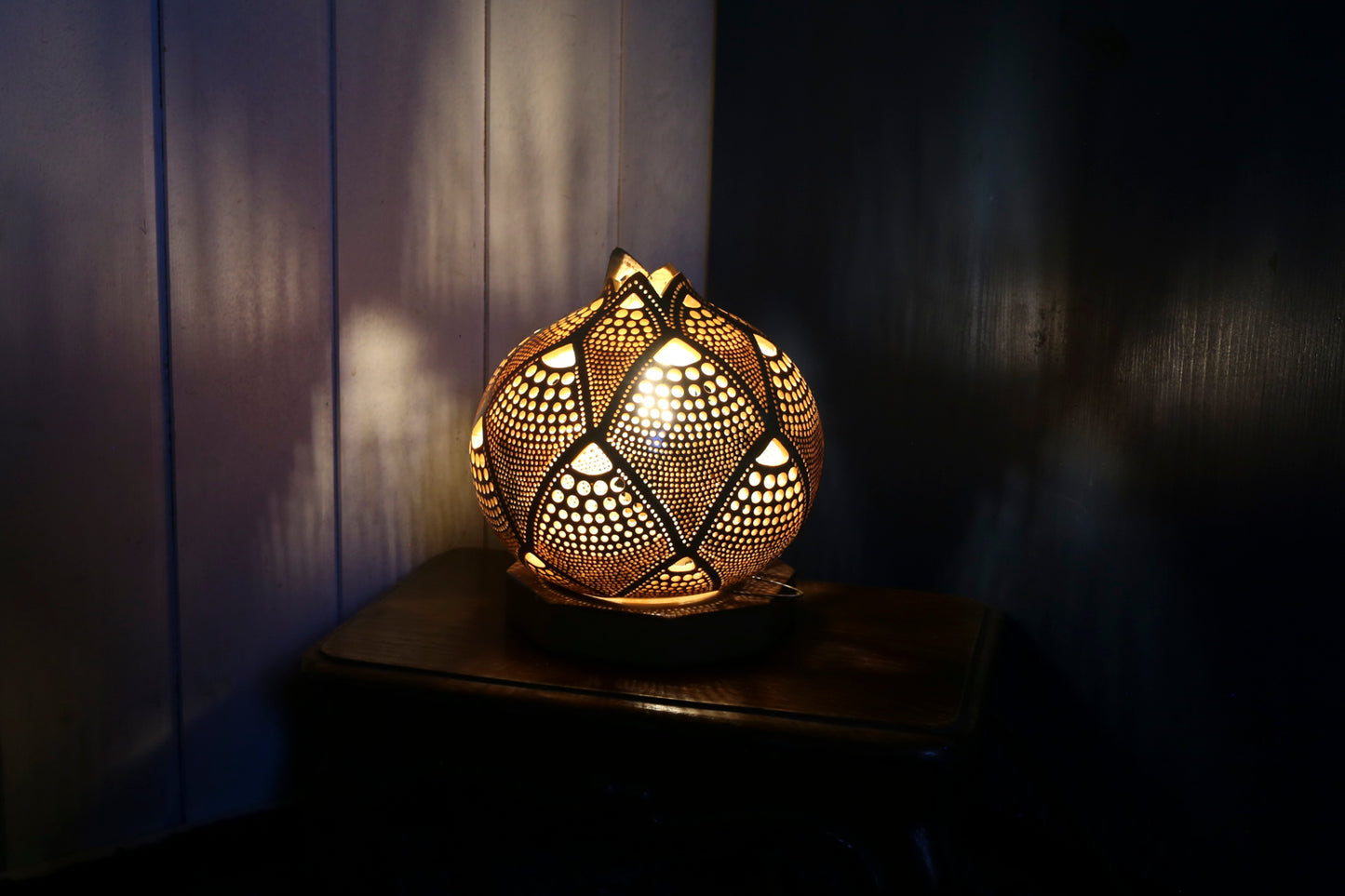 Decorative lamp with intricate design on a wooden surface in a dimly lit room.
