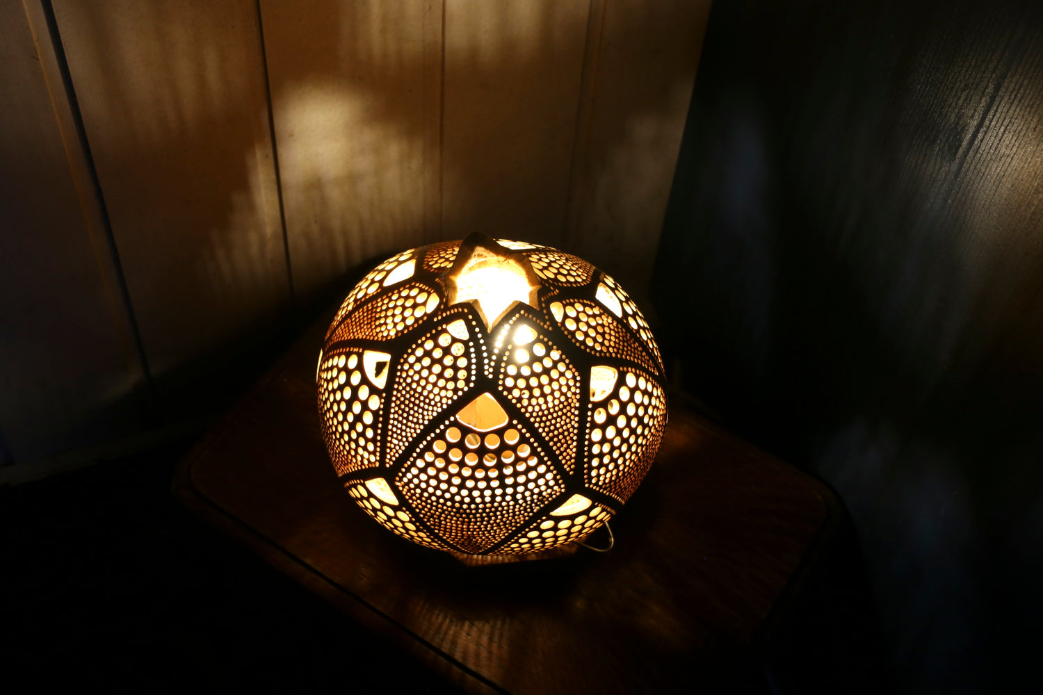 Decorative spherical lamp with intricate patterns on a wooden surface.