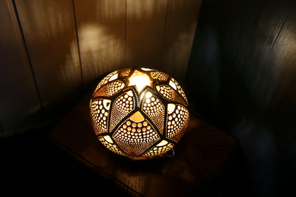 Decorative spherical lamp with intricate patterns on a wooden surface.