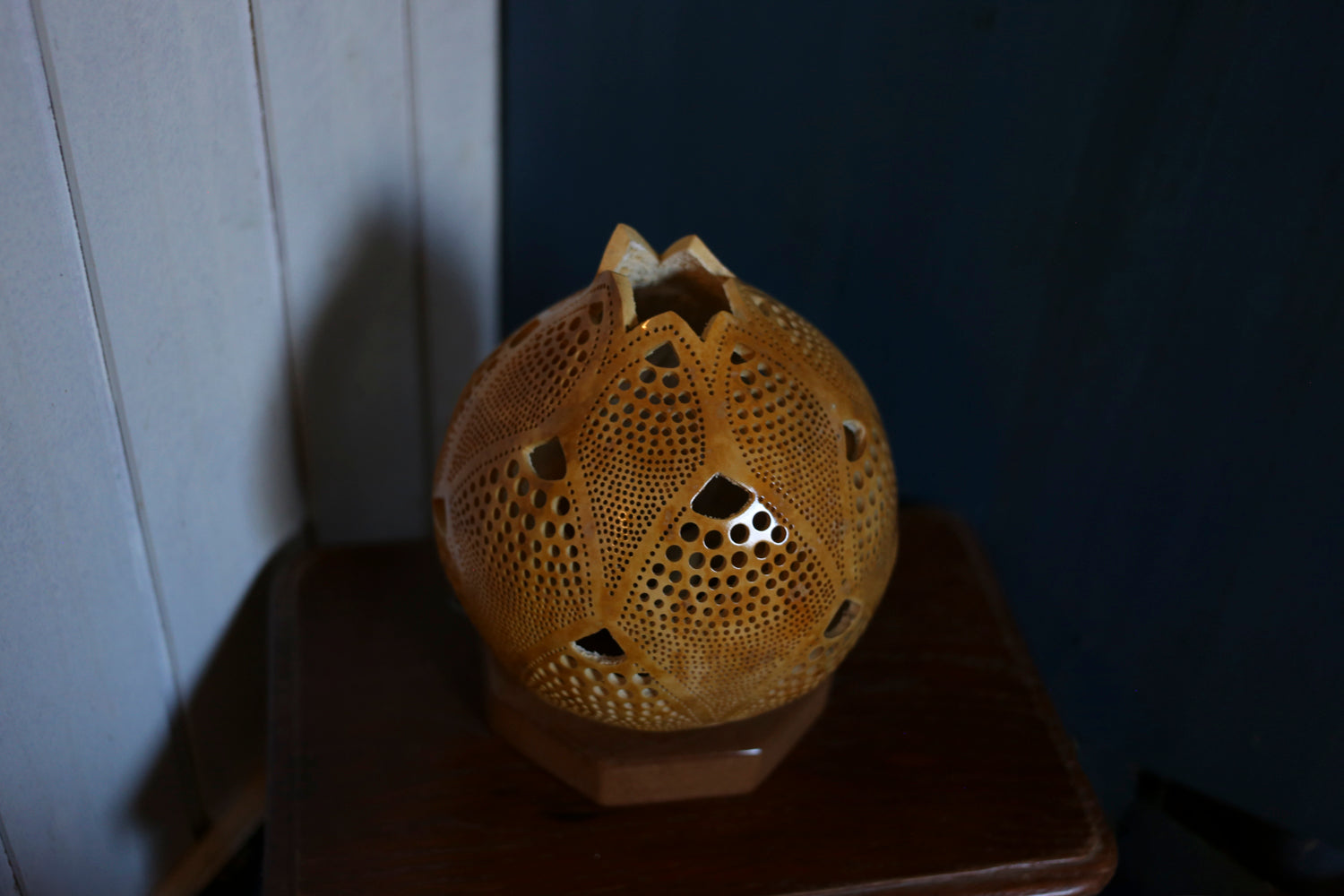 Decorative gourd lamp with intricate design on a dark surface