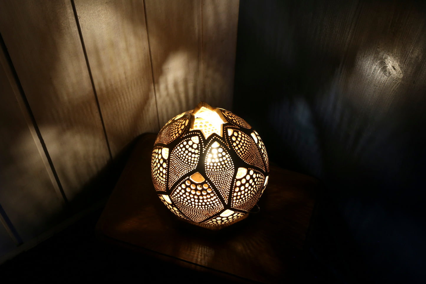 Decorative spherical lamp with intricate patterns on a wooden surface.