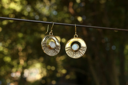 brass earrings with a moonstone against a blurred natural background