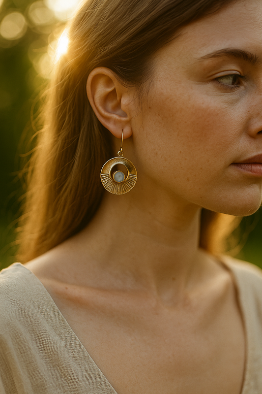 Close-up of a woman wearing brass earrings with a blurred natural background
