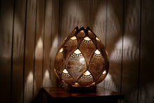 Load image into Gallery viewer, Image of a handcrafted calabash lamp. The gourd&#39;s surface is intricately carved with patterns that allow soft light to shine through, creating a warm and inviting ambiance. The lamp is a blend of natural elegance and artistry, casting gentle shadows that enhance its beauty