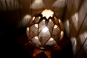Image of a handcrafted calabash lamp. The gourd's surface is intricately carved with patterns that allow soft light to shine through, creating a warm and inviting ambiance. The lamp is a blend of natural elegance and artistry, casting gentle shadows that enhance its beauty