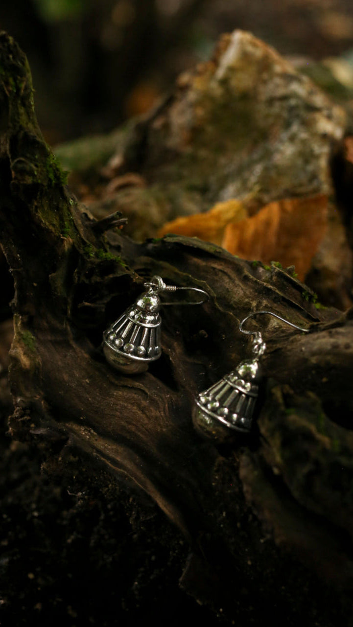 Silver earrings on a textured surface with a natural background