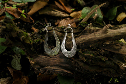 Silver hoop earrings on a wooden surface with a natural background