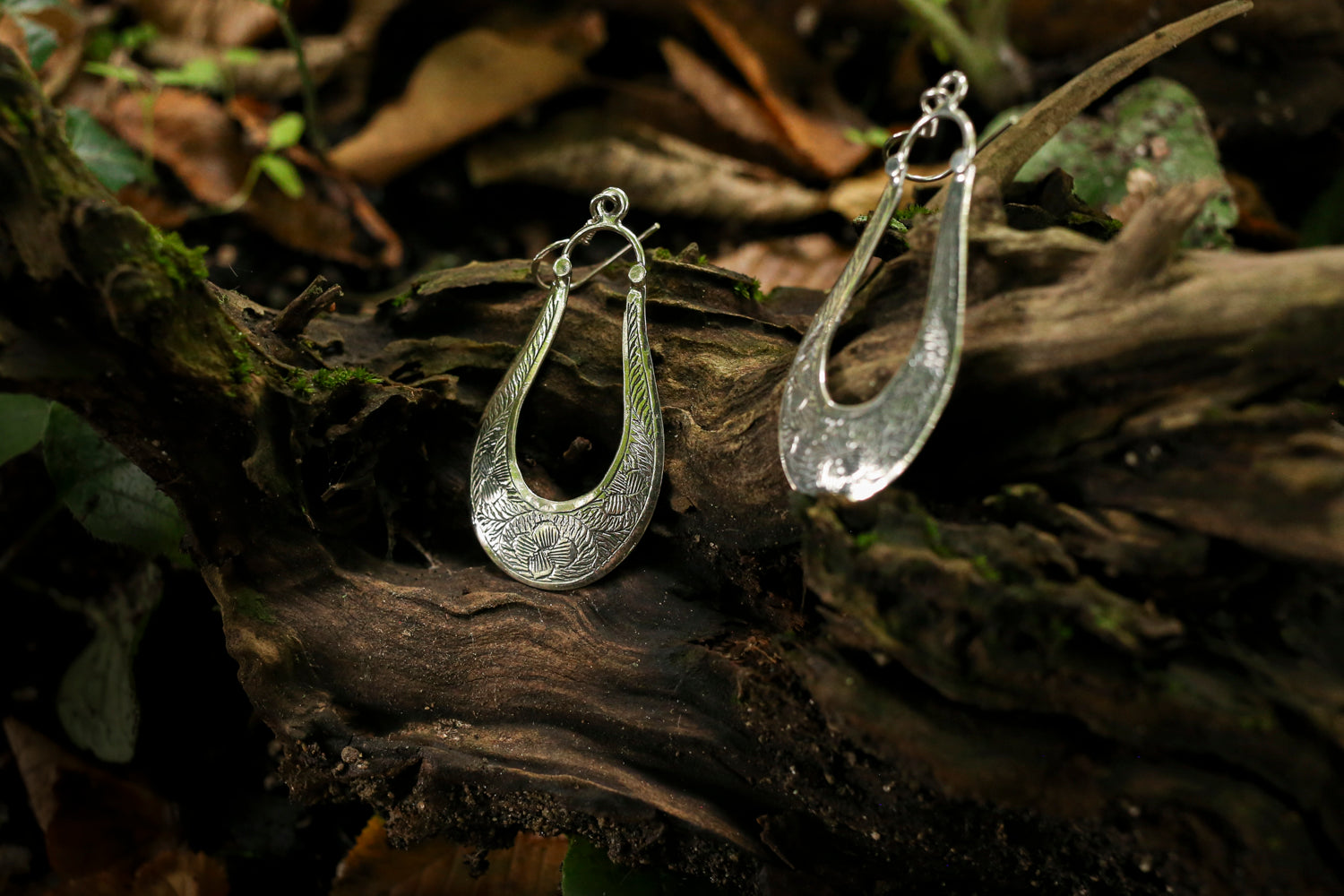 Silver hoop earrings on a wooden surface with a natural background